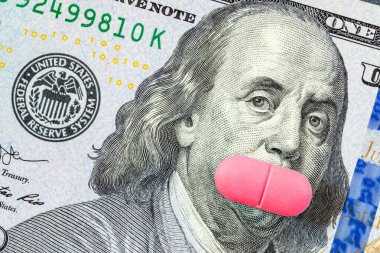 Pembe bir hap Franklin 'in ağzını yüz dolarlık banknotla kaplıyor. Feminizm kavramı, kadın sağlığı, doğum kontrol haplarının maliyeti veya komplo teorisi.