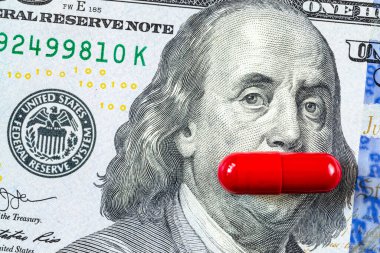 Kırmızı bir hap Franklin 'in ağzını yüz dolarlık banknotla kaplıyor. İktidar kavramı, sağlık, hap maliyeti, erkek sağlığı