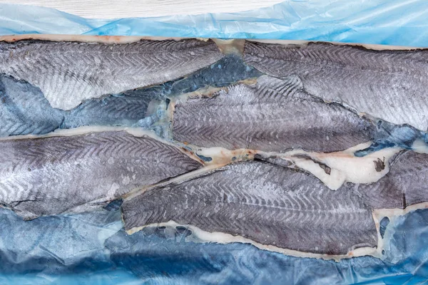 Frozen fish Longtail hake for sale at wholesale fish market. Lots of fish on the counter. Close-up