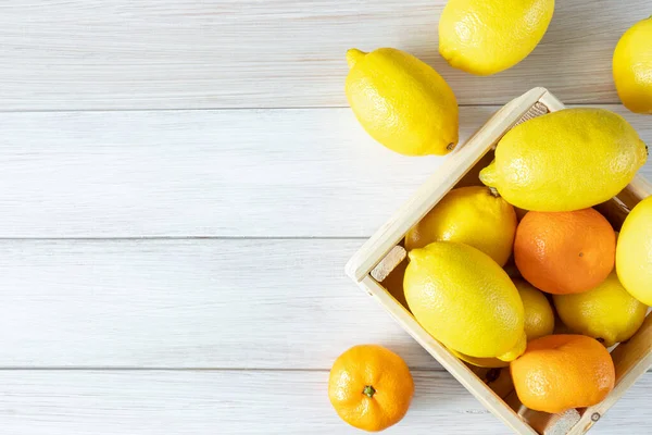 柠檬和达林在一个木箱里 新鲜的橘子和柠檬 白色的木制背景 顶部视图 成熟可口的柑橘类水果 复制空间 图库照片