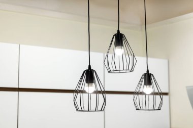 Siyah metalden yapılmış modern bir tavan arası avizesi. Beyaz bir iç mekan. Modern tel tavan ışıkları. Seçici odak