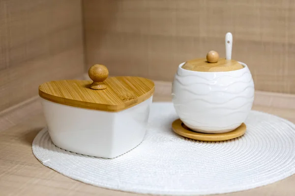 キッチンテーブルの上には 白いセラミックシュガーボウルと木製の蓋付きのキャンディーボウル 選択的焦点 — ストック写真