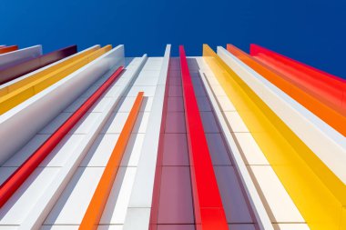 Mavi gökyüzü arka planında çok renkli plastikle dekore edilmiş bir duvar parçası. Dikey perspektif