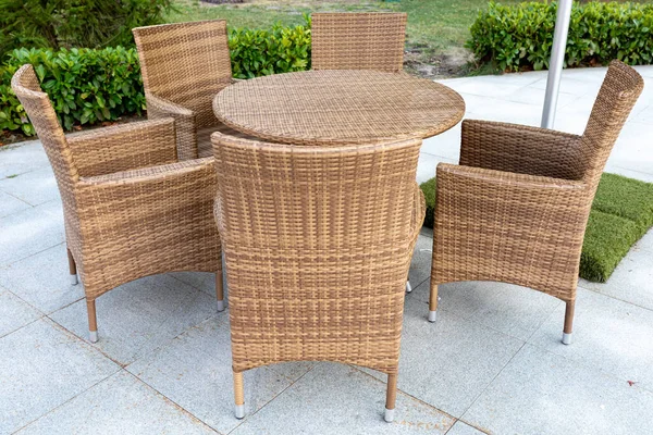 Rattan wicker furniture: table and chairs in an outdoor cafe or park. Close-up