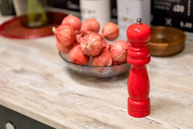 Süslü yapay sarımsağın yanında parlak kırmızı bir biber değirmeni. Modern bir mutfağın dekorasyonu. Seçici odak