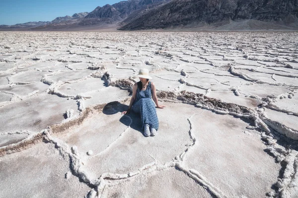 Salt Flats in Death Valley National Park. Silhouette of woman enjoying view. Badwater Basin hiking trail, trail adventure through upheaved salt plates below sea level.