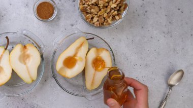 Cevizli fırında armut, bal ve tarçın, kırsal arka planda yakın çekim, mükemmel kahvaltı veya tatlı, düz yatak, kadın eli