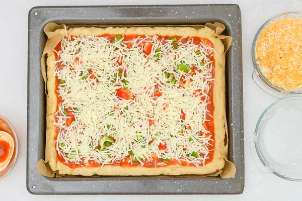 Uncooked vegetarian pizza on baking pan, close up view from above