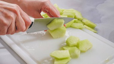 Honeydew kavunu kesme tahtasına yakın. Kavun doğrayan kadın, meyve salatası hazırlama süreci