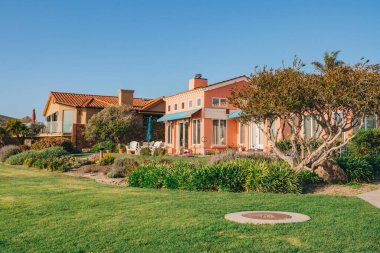 Bahçesi güzel manzaralı güzel evler ve Kaliforniya 'da küçük bir sahil kasabasında arka planda açık mavi gökyüzü..