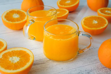 Portakallar ve taze sıkılmış portakal suyu hafif ahşap arka planda kapanıyor.