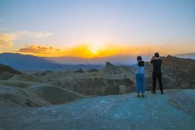 Ölüm Vadisi, Kaliforniya, ABD... 14 Nisan 2021 Zabriskie Point Sunset, Ölüm Vadisi Ulusal Parkı 'nda gün batımını görmek için en popüler yerlerden biri. Vadiye bakan turistler.