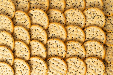 Susam ve haşhaşlı krakerler yukarıdan yaklaşıyor. Gıda arka planı, tam çerçeve