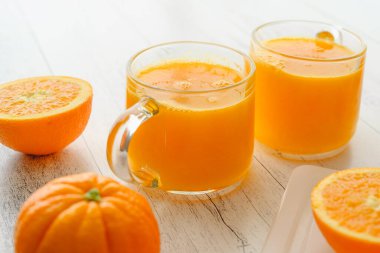 Portakallar ve taze sıkılmış portakal suyu. Hafif ahşap arka plana yakın, düz uzanmış.