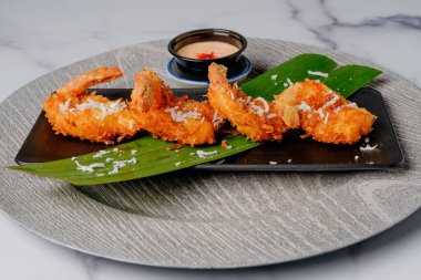 Kızarmış hindistancevizli karides. Kokteyl sosuyla servis ediliyor. Tabağa yakın.