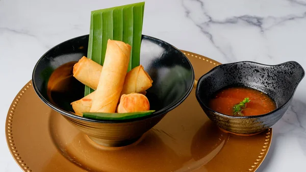 Crispy veggie rolls. Traditional Chinese Thai restaurant appetizer, spring rolls  filled with Chinese veggies, close up on a plate served with chili dipping sauce.