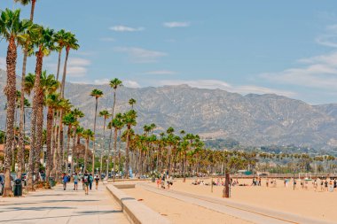 Santa Barbara, California, USA - August 1, 2022  Santa Barbara beach promenade with walking people, sandy beach, and mountains and cloudy sky on background