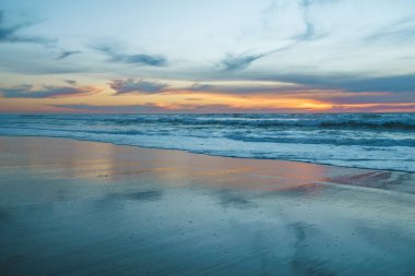 Manzaralı deniz manzarası, okyanusun üzerinde gün batımı. Sakin sahne, güzel güneş yansıması ve fırtınalı okyanus dalgaları.