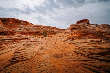 Red wavy sand stones, bluffs and cliifs at Glen Canyon National Recriation Area, Page, Arizona, and dramatic cloudy sky background
