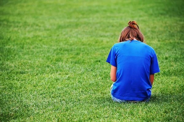 Jeune fille assise sur l'herbe — Photo