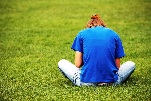 Jeune fille assise sur l'herbe — Photo