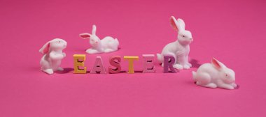 Bayram afişi Mutlu Paskalya ahşap kelimeleri ve turkuaz arka planda şirin Paskalya tavşanları.