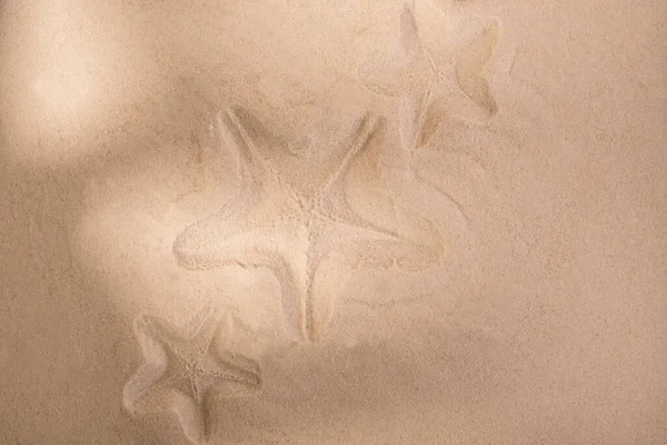 Zeesterren sporen op een zandoppervlak. Summerbackground goed voor seizoensgebonden verkoop of Tour Trip aankondiging. — Stockfoto