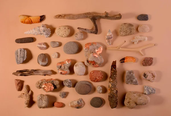 Zestaw różnych kamieni morskich i drewnianych kijów na tle koloru piasku widok z góry — Zdjęcie stockowe
