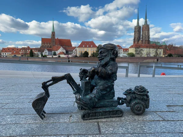 Polonya, Wroclaw, 16 Nisan 2022. Ünlü bronz minyatür cüce Tumski Adası tapınağının önündeki kazıcıyı kazıyor..