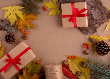 Autumnal Gifts. Gift Boxes Wrapped in Craft Paper Banded with Red Ribbon decorated with fall leaves. Thanksgiving day concept.