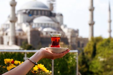 Türkiye 'nin İstanbul kentindeki Sultanahmet Camii' nin arka planında bir bardak Türk çayı.