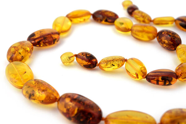 Балтийское ожерелье из натурального полированного прозрачного меда роскошные янтарные бусины с включениями на белом. Закрыть избирательный мягкий фокус. Пространство для текста