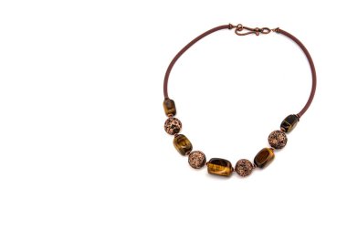 Yeşil mücevher sıralı kaplan gözlü kahverengi taş zincir. Beyaz arka planda klasik, zarif bir kolye. Kadın aksesuarları, dekoratif süsler. Moda ve tarz kavramı.