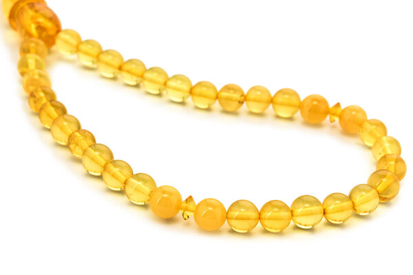 Балтийское ожерелье из натурального полированного прозрачного меда роскошные янтарные бусины с включениями на белом. Закрыть избирательный мягкий фокус. Пространство для текста