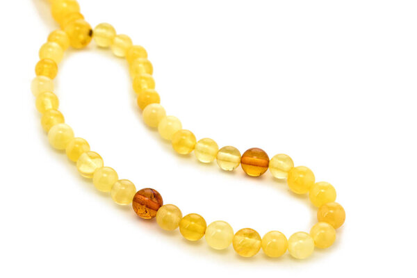 Балтийское ожерелье из натурального полированного прозрачного меда роскошные янтарные бусины с включениями на белом. Закрыть избирательный мягкий фокус. Пространство для текста