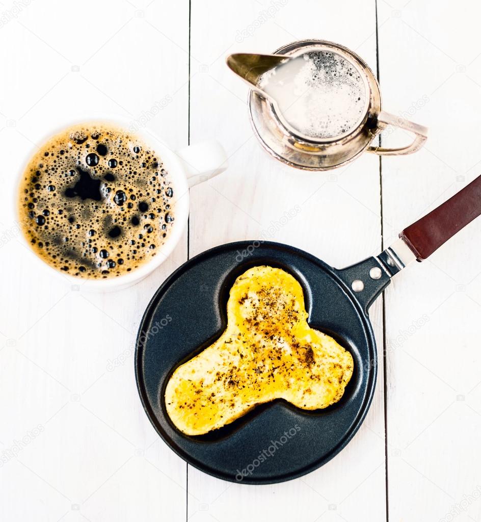 Fried eggs in fun form of man penis in a frying pan with coffee