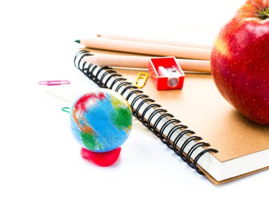 Küre ve beyaz zemin üzerine defter ile okul malzemeleri.