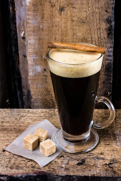 Hög kopp espressokaffe i glas med kanelstång på gamla rustika träbord — Stockfoto