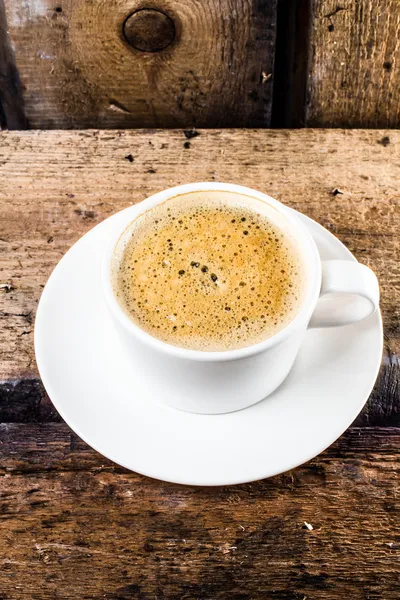 Café capuchino con espuma sobre platillo blanco sobre fondo de madera vieja grange . — Foto de Stock