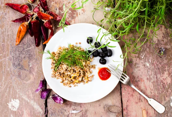 Boiled buckwheat, pepper, black olives and herbs on white plate — Stock Photo, Image