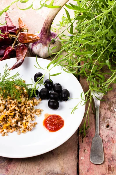 Гречка, перец, черные оливки и травы в белом блюде — стоковое фото