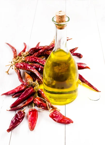Vasetto con bottiglia di olio d'oliva e grappolo con peperone rosso essiccato su fondo bianco . — Foto Stock