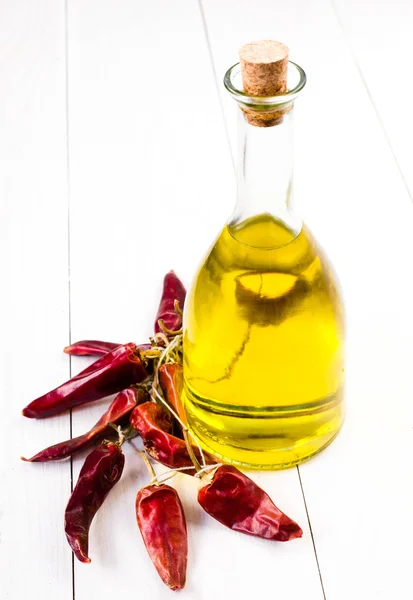 Bottiglia di olio d'oliva e peperoncino rosso su fondo di legno bianco . — Foto Stock