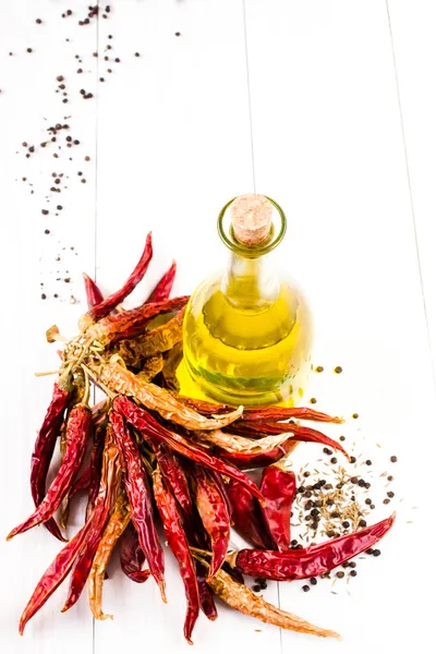 Vaso con olio d'oliva e grappolo con peperone rosso essiccato su fondo bianco . — Foto Stock
