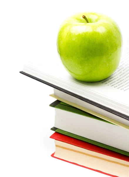 Open Book heap and green apple on top over white background — Stock Photo, Image