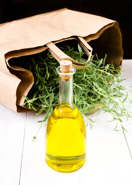 Bottiglia di olio d'oliva ed erbe aromatiche con sacchetto di carta su fondo di legno bianco . — Foto Stock