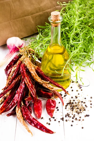 Bottiglia di olio d'oliva, erbe aromatiche, aglio e peperoncino rosso su sfondo bianco — Foto Stock