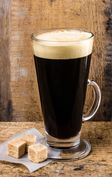 Café expreso de alta taza de vidrio con cubos de caña en la vieja mesa rústica de madera — Foto de Stock