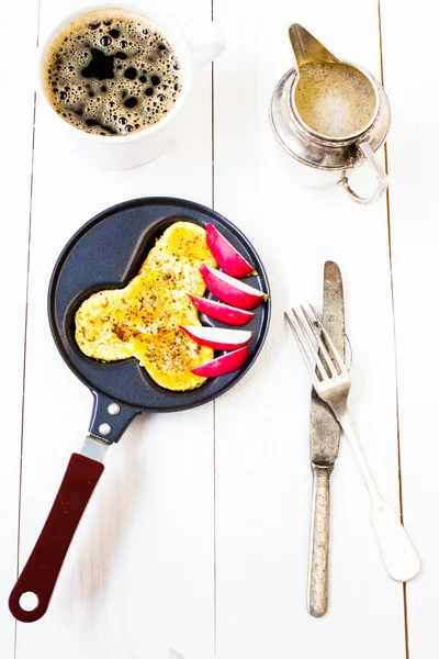 Fried fresh eggs in fun form of man penis in a frying pan with coffee and milk over white wooden backgroun — Stock Photo, Image