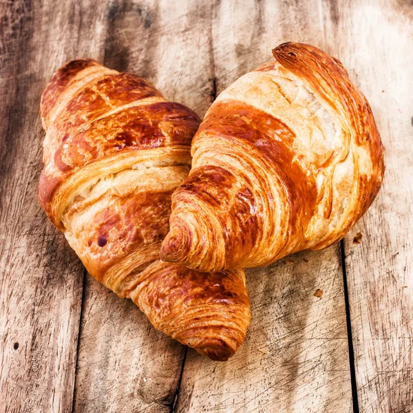 Croissant freschi su sfondo rustico in legno — Foto Stock